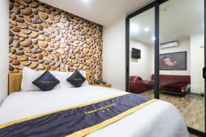 ホーチミン・シティにあるMINH THƯ HOTELの石壁のベッドルーム1室(大型ベッド1台付)