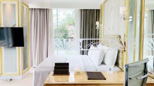 1 dormitorio con 1 cama y 1 mesa con TV en Art Deco Luxury Hotel & Residence en Bandung