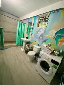 a bathroom with a toilet and a washing machine at Zen Cove w/rental vehicle access in Gros Islet