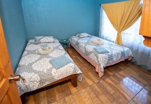 two beds in a room with blue walls at Casa Encanto in Puntarenas