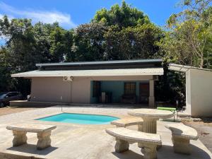 a pool with two benches in front of a building at Casa Encanto in Puntarenas