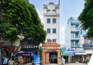 ein weißes Gebäude mit einem Uhrturm in einer Straße in der Unterkunft MINH THƯ HOTEL in Ho-Chi-Minh-Stadt