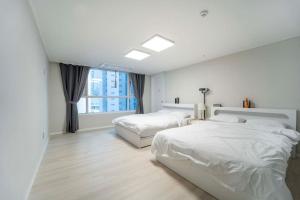 1 dormitorio blanco con 2 camas y ventana en Haeundae Chocho house stay 1, en Busan