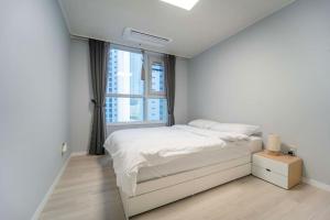 um quarto branco com uma cama e uma janela em Haeundae Chocho house stay 1 em Busan