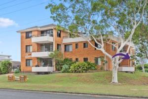 a brick building with a tree in front of it at Modern Retro Retreat in Tuncurry