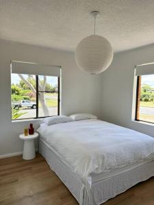 a white bedroom with a bed and a pendant light at Modern Retro Retreat in Tuncurry