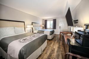 a hotel room with two beds and a flat screen tv at RIVER OAK INN in Bandera