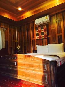 a bedroom with a bed with a fan on the wall at Sirilagoona Home Resort in Nong Prue
