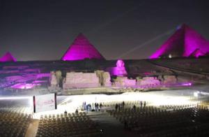Un groupe de personnes debout devant les pyramides la nuit dans l'établissement Lotus Pyramids Hotel, au Caire