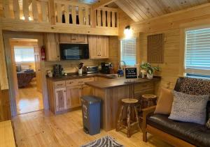 a kitchen and living room in a log cabin at Serene 1BR Cabin near NC Z00 with Loft & Waterview in Asheboro