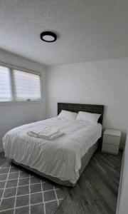 1 dormitorio con 1 cama grande con sábanas blancas en Cozy en Regina