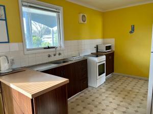 a kitchen with yellow walls and a white stove top oven at Robey - Robe in Robe