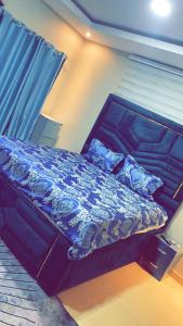 a bed with a blue comforter and pillows on it at Magic City Apartments in Kasoa