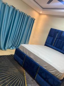 łóżko w pokoju z niebieską zasłoną w obiekcie Magic City Apartments w mieście Kasoa