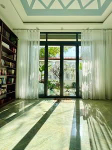 a living room with a large glass door with curtains at The Hygge House in Da Nang