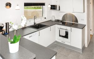 a kitchen with white cabinets and a sink at Holiday Home Fiskervej Sydals I in Skovby