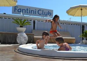three children playing in a swimming pool with a woman at Fantini Club Hotel in Cervia
