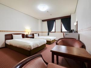 富山市にあるecoHotelのベッド2台、テーブルと椅子が備わるホテルルームです。