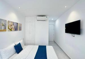 a white bedroom with a bed and a flat screen tv at Thinh Vuong Apartment IX in Ho Chi Minh City