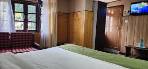 a hotel room with a bed and a television at Veronica Alpina Mountain View Home in Darjeeling