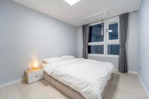 a white bedroom with a bed and a window at Haeundae Chocho stay 2 in Busan