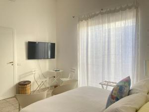 a bedroom with a bed and a window with a tv at fuoridalgusciohome in Leuca