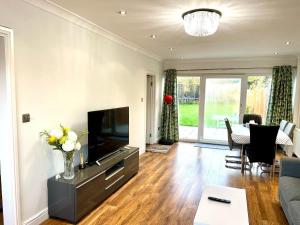 a living room with a television and a table at Greenfield's Halkingcroft Home - Modern 3-bedroom house in Langley, SL3 7BB in Slough