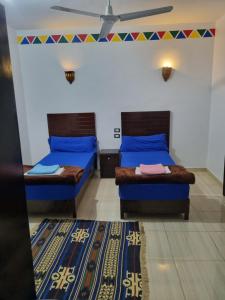 a room with two beds and a rug at ABAZIDO Nubian Guest House in Aswan