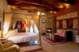 a bedroom with a large bed and a fireplace at Aiolides Hotel in Kalyvia