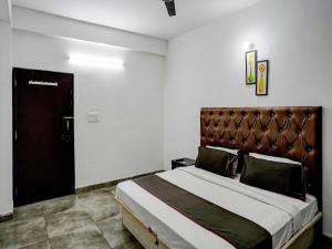 グルガオンにあるSuper Hotel O Omi Roomsのベッドルーム1室(大型ベッド1台、革張りのヘッドボード付)