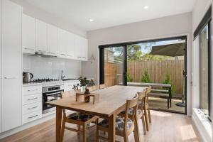 a kitchen and dining room with a wooden table and chairs at Beachside Townhouse in Rosebud