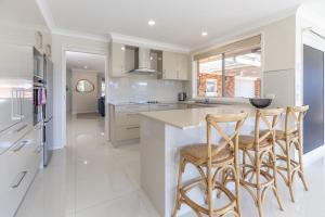 a kitchen with white cabinets and a island with bar stools at 114 Elizabeth Pde in Forster