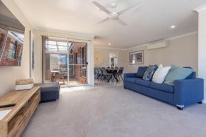 a living room with a blue couch and a ceiling fan at 114 Elizabeth Pde in Forster