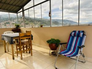 einen Balkon mit einem Tisch, Stühlen und Fenstern in der Unterkunft Yerupaja Mountain Hostel in Huaraz