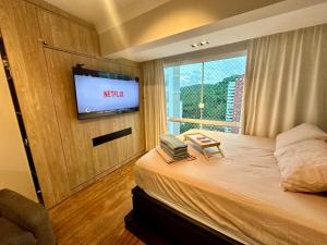 um quarto de hotel com uma cama e uma televisão em Studio Pé na Areia II em Balneário Camboriú