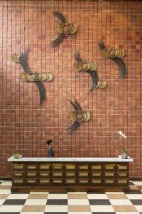 a person walking past a wall with birds on it at THE 1O1 Yogyakarta Tugu in Yogyakarta