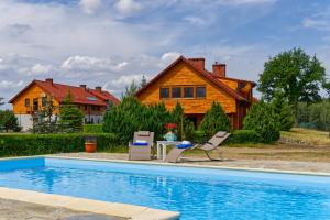 a house with a pool and two chairs and a house at Funaberia -25 hektarowa luksusowa posiadłość z basenem, jacuzzi, sauną, boiskiem wielofunkcyjnym in Skop