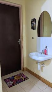 W łazience znajduje się biała umywalka i lustro. w obiekcie Kinyanjui's Homes 001 with WiFi w mieście Morogoro