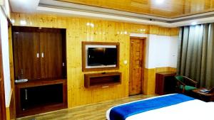 a bedroom with a bed and a tv on a wooden wall at Humble Holiday Inn Kufri Simla in Shimla