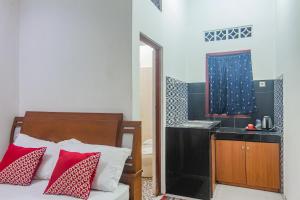 um quarto com uma cama com almofadas vermelhas e um lavatório em OYO 93691 Minongga em Jakarta