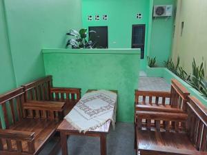 two wooden benches in a room with green walls at OYO 93695 Guest House Riharti Syariah in Bandar Lampung