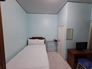 um pequeno quarto com uma cama e uma televisão em OYO 93695 Guest House Riharti Syariah em Bandar Lampung