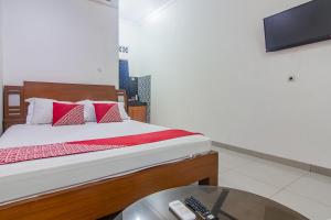 um quarto com uma cama, uma televisão e uma mesa em OYO 93691 Minongga em Jakarta