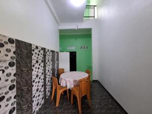 uma mesa e cadeiras num quarto com uma parede verde em OYO 93695 Guest House Riharti Syariah em Bandar Lampung