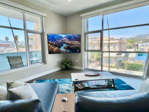 a living room with a couch and a table and windows at Large Hollywood Corner 2 Bedroom with Private Balcony in Los Angeles
