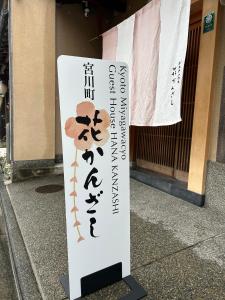 un panneau sur le trottoir devant un bâtiment dans l'établissement Gion Kyoto Miyagawacyo Guesthouse HANAKANZASHI, à Kyoto