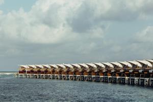 ein Gebäude auf einem Pier im Wasser in der Unterkunft Cinnamon Hakuraa Huraa Maldives - All Inclusive in Meemu Atoll