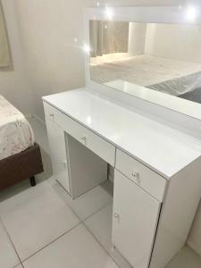 uma casa de banho com um toucador branco e um espelho. em Apartamento grande Florianópolis próximo arena opus em São José