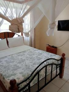 1 dormitorio con 1 cama y una ventana con cortinas en Diani Breeze Villas, en Diani Beach