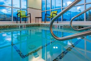 a swimming pool with blue water and yellow chairs at SpringHill Suites by Marriott Gallup in Gallup